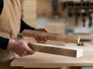 mani che confrontano due listelli di legno su un banco da lavoro