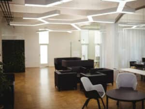 open space con pavimento in legno, divani scuri e sedute bianche